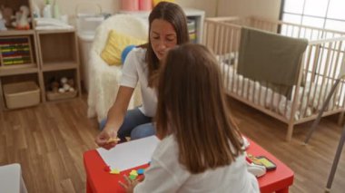 Çocuklarla oyuncak, ahşap mobilya ve beşik içeren rahat bir kreş odasında oynayan bir kadın, eğitim faaliyetleriyle sıcak bir aile ortamı yaratıyor..