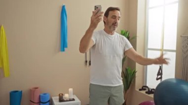 Modern bir kaplıcada yoga minderleri ve dekorları olan, rahatlama ve iletişimi ön plana çıkaran bir video sırasında İspanyol bir adam sağlık seansının keyfini çıkarıyor..