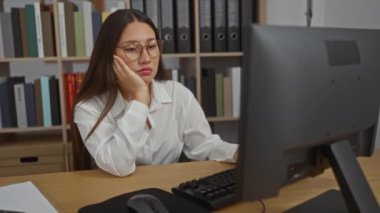 Ofiste masa başında esneyen yorgun bir kadın bilgisayar ekranına bakıyor.