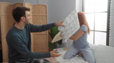 Sıcak yatak odasında şakacı bir yastık kavgasına tutuştular, doğal ışık ve günlük kıyafetlerle bir ev ortamında neşe ve aşkı ifade ettiler, eğlenceli, samimi bir an yakaladılar..