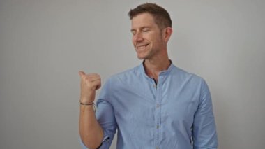 Sade arka planda mavi tişört giyen bir adam izole bir ortamda kendine güvenen bir ifade sergiliyor.