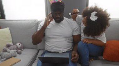 Baba ve kızı oturma odasında dizüstü bilgisayarla birbirlerine bağlanıyorlar. O telefonda konuşurken, o da kafasını kurnazca dekore ediyor. Aile sevgisini ve birlikteliğini gösteriyor..