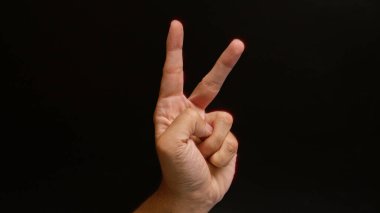 Adamın eli karanlık bir arka plana karşı barış işareti yapıyor.