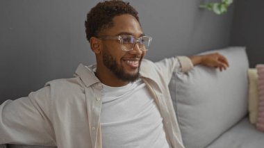 Evdeki rahat bir oturma odasında rahat bir kanepe ve şık bir dekorla rahatlayan yakışıklı genç adam.