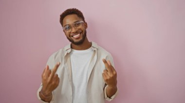 Gözlük takan genç adam, iki orta parmağıyla pembe arka planda müstehcen bir hareket yapıyor.