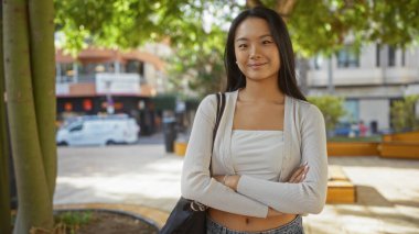 Şehir parkında kendine güvenen bir kadın, güzel ve çekici genç Çinli bir kadını şehir dışında sokak ortamında sergiliyor..