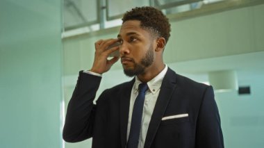 Ofis ortamında telefonundan sesli mesaj dinleyen genç adam.