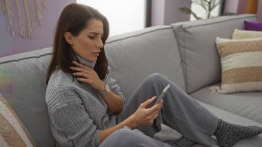 Oturma odasındaki koltukta dinlenen, rahat bir kadın. Telefonla konuşan, düşünceli, süveter giyen, rahat bir ev ortamında öğleden sonra barışı sağlayan bir kadın..