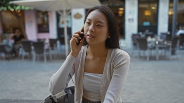 Şehir merkezinde gündüz vakti telefonla konuşan bir kadın.