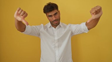 İzole edilmiş sarı arka planda beyaz gömlek giymekten hoşlanmayan genç bir adam var.