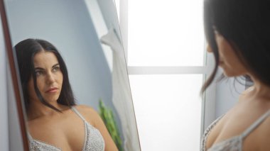 Kaplıca salonundaki yansımasına bakan bir kadın kapalı bir ortamda güzellik ve sağlığını sergiliyor..