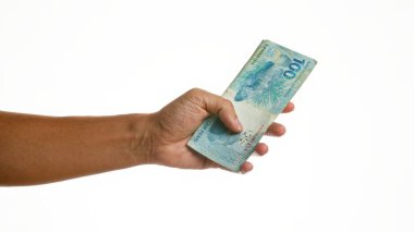 İzole edilmiş beyaz arka planda Brezilya reais 'i tutan adam.