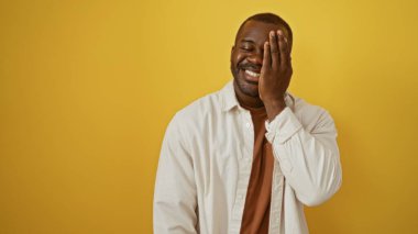 Genç Afro-Amerikan adam gülümsüyor ve yüzünü kapatıyor.