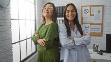 Ofis ortamında kolları bağlı iki kendine güvenen kadın, çalışanlar arasında takım çalışması ve liderlik örneği teşkil ediyor..