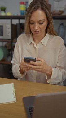 Samimi ofis ortamında ahşap dizüstü bilgisayarlı akıllı telefon kullanan bir kadın ve çağdaş bir çalışma ortamı sergileyen modern bir dekor.