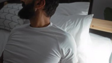 Sakallı yakışıklı adam yatak odasında uzanıyor.