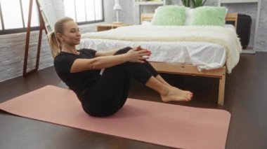 Yoga minderi üzerinde egzersiz yapan bir kadın modern dekor ve doğal ışıkla, spor salonuna odaklanıyor..