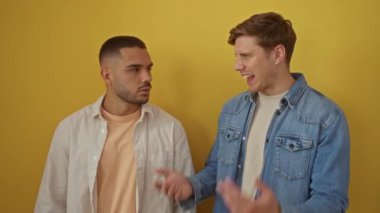 İki adam dostça bir etkileşim içindeler, biri bağırıyor, diğeri ise kulaklarını parlak sarı bir duvara yaslıyor, neşeli bir anlaşmazlığı gösteriyor..