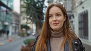 Şehirdeki şehir caddesinde gülümseyen bir kadın, kendine güvenen bir ifade sergiliyor. Uzun saçlı ve gündüzleri giydiği kıyafetlerle modern yaşam tarzı cazibesini sergiliyor..