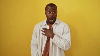 Afro-Amerikalı gömlekli, kuşkucu, alaycı, ağzı açık, izole edilmiş sarı arka planı olan bir adam.