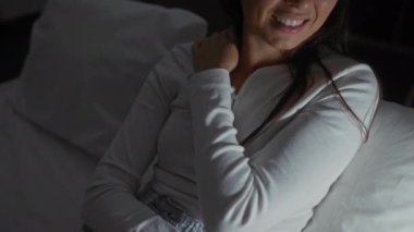 Kadın kapalı bir odada dinleniyor, boynunu düşünceli bir ifadeyle tutuyor, rahat ve rahat bir ev ortamını gece boyunca tasvir ediyor..