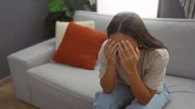 Oturma odasında başka bir kadını teselli eden bir kadın, yüzünü örten bir kadın, ev ortamında destek, rahatlık ve duygusal bağ kuran bir kadın.