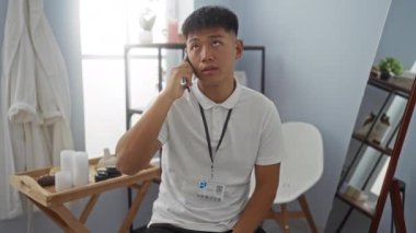 Genç adam ahşap bir masası ve rahatlatıcı bir atmosferi olan parlak bir spa odasında telefonla konuşuyor.