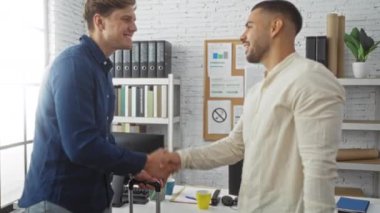 Işıl ışıl bir ofiste el sıkışan iki adam iş, ortaklık ve takım çalışmasını profesyonel bir iş ortamında paylaşıyorlar..