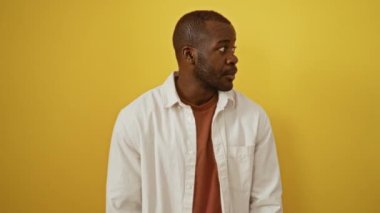 Gömlekli Afro-Amerikan bir adam, ağzı ve eliyle izole edilmiş sarı arka planda konuşmalar fısıldıyor.