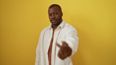 Orta parmağıyla ayakta dikilen Afro-Amerikalı bir adam izole edilmiş sarı arka planda kaba ve kaba bir ifade sergiliyor.