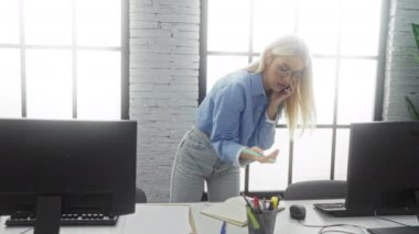 Parlak modern ofis ortamında çalışan, notlara ve bilgisayar görevlerine odaklanan, dinamik, profesyonel bir atmosfer yaratan bir kadın telefonda konuşuyor..