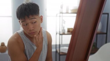 Genç bir adam aynada yüzünü inceliyor. Bir sağlık merkezinde.