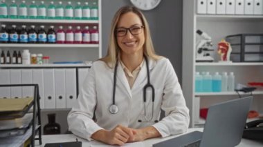 Hastanenin içinde, masasında steteskopla gülümseyen bir kadın sağlık hizmetleri promosyonu için uygun profesyonel ve kendinden emin bir atmosfer sunuyor.