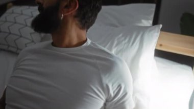 Sakallı yakışıklı adam yatak odasında uzanıyor.