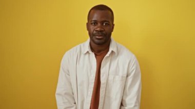 Yüzünde barış sembolü olan tişört giyen Afro-Amerikan bir adam, neşeli parmakları olan, neşeli zafer gösteren, parlak sarı arka plana karşı izole edilmiş,