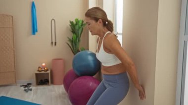 Spor salonunda egzersiz yapan bir kadın orta yaşlı bir kadın spor merkezinde duvar çömelmesi yapıyor.
