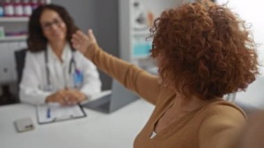 Klinikte kadın doktorla selfie çeken orta yaşlı İspanyol kadın, sağlık hizmetleri ve hasta-doktor etkileşimine dikkat çekiyor.