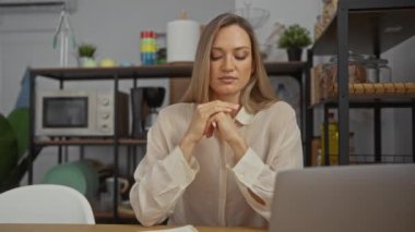 Kadın modern ekipmanlarla şık ofis ortamında, dizüstü bilgisayar ve defterle masada otururken bunalmış hissediyor..