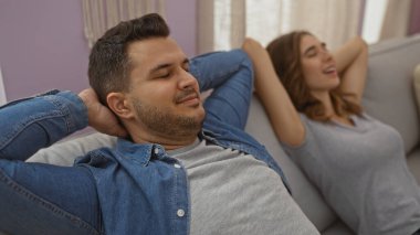 Couple relaxing together on the couch at home with a man and a woman smiling and enjoying their time indoors in a comfortable living room. clipart