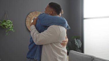 Erkek arkadaşlar sıcak bir oturma odasında sarılırlar, modern bir apartman dairesinde sıcak ve duygusal bir bağ sergilerler.