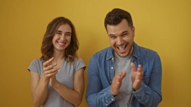 Sarı arka planda izole edilmiş, gülümseyen ve mutluluğu gösteren kadın ve erkek el çırpıyor.