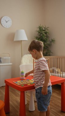 Küçük çocuk evde rahat bir anaokulunda yapboz oynuyor. Gün ışığıyla aydınlatılıyor.