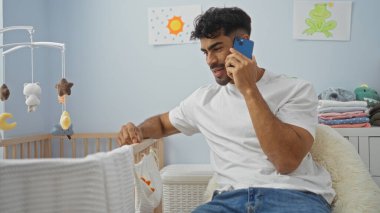 Yatak odasında beşikte beşiği olan genç bir adam neşeli atmosferli ve parlak dekorlu bir ev hayatı görüntüsü öneriyor..