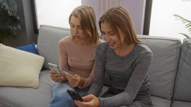 Kadınlar internet üzerinden kredi kartı ve telefonlarıyla alışveriş yapıyor, rahat bir oturma odasında birlikte oturuyor, dijital yaşam tarzlarını ve modern aile bağlarını sergiliyor..