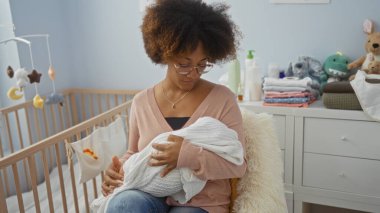 Bebek beşiği gibi rahat bir yatak odasında yumuşak pastel tonlar ve anne olma anını yansıtan bebek esasları olan bir kadın..