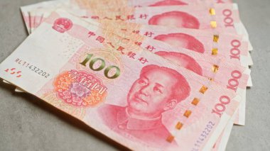 Çin Yuan banknotları somut bir yüzeye yayılmış, para biriminin, dokunun ve ikonik figürün detaylarını resmediyor..