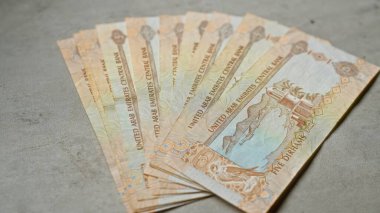 Birleşik Arap Emirlikleri banknotları somut bir yüzeye yayılmış ayrıntılı tasarımlar ve Arapça metinler sergiliyor, finans temaları ve Orta Doğu para birimini temsil ediyor.