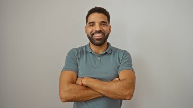 Yakışıklı, İspanyol asıllı, kolları bağlı, özgüvenle gülümseyen bir adam.