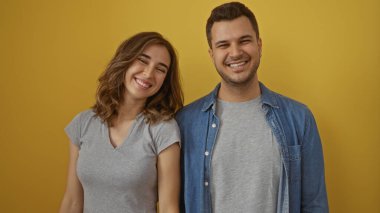 Sarı arka planda birlikte gülümseyen erkek ve kadın mutlu bir ilişkide sevgi ve neşe gösteriyorlar..