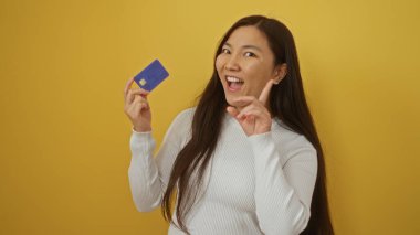 Modern minimalist ortamda canlı sarı duvara karşı güvenle gülümseyen kadın kültürel çeşitliliği ve finansal bağımsızlığı vurguluyor.